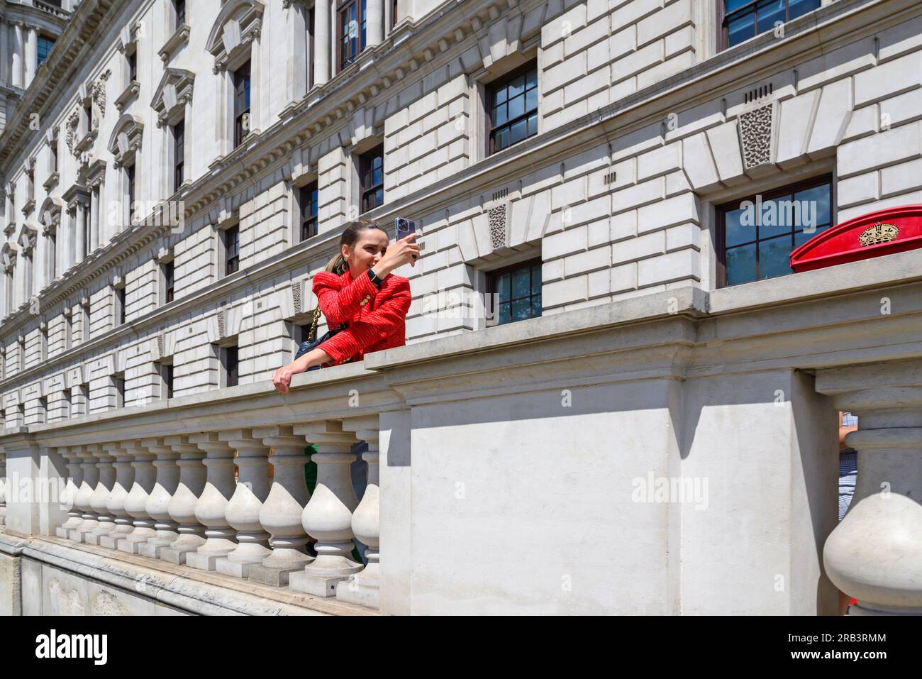 London, Großbritannien. Junge Frau in Rot, die ein Selfie auf dem Parlamentsplatz in Westminster macht Stockfoto
