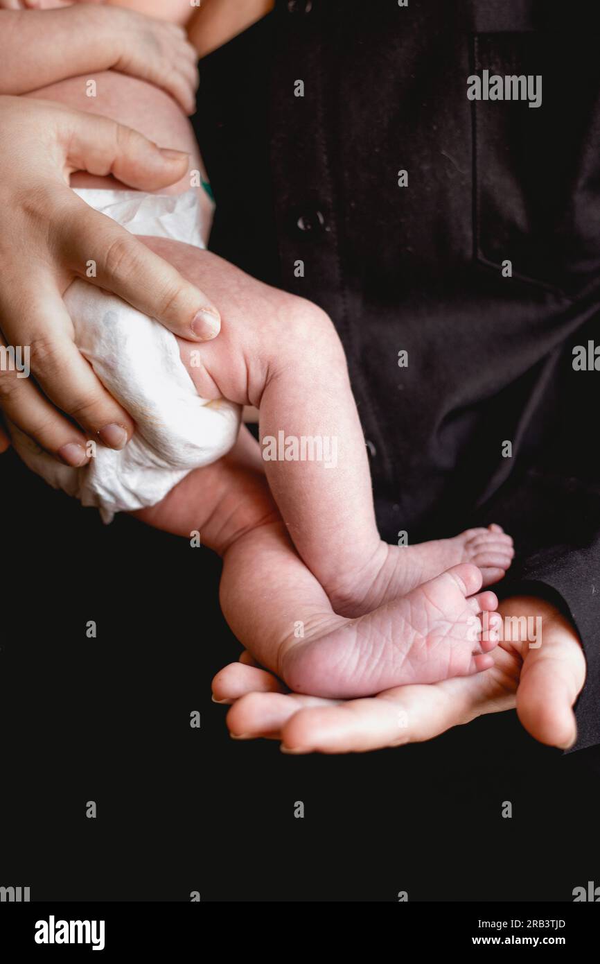 Mutter, die die winzigen Füße des Neugeborenen hält Stockfoto