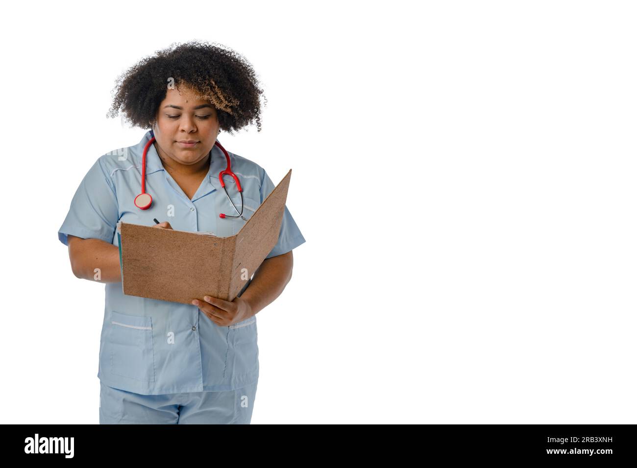 Junge Afro-lateinische Ärztin in blauer Uniform, schreibt und liest medizinische Akten in einem braunen Ordner, weißer Hintergrund mit Kopierbereich Stockfoto