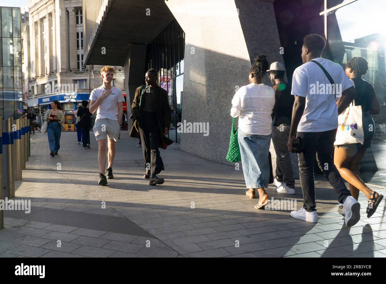 Wetter in Großbritannien, 6. Juli 2023, London: Nach ein paar kälteren Tagen kehrt das warme Wetter nach London zurück und bringt Menschenmassen nach Soho. Am Mittelpunkt kommt Licht aus allen Richtungen, da es von Plattenglasfenstern reflektiert wird, die Schatten in verschiedene Richtungen werfen. Kredit: Anna Watson/Alamy Live News Stockfoto
