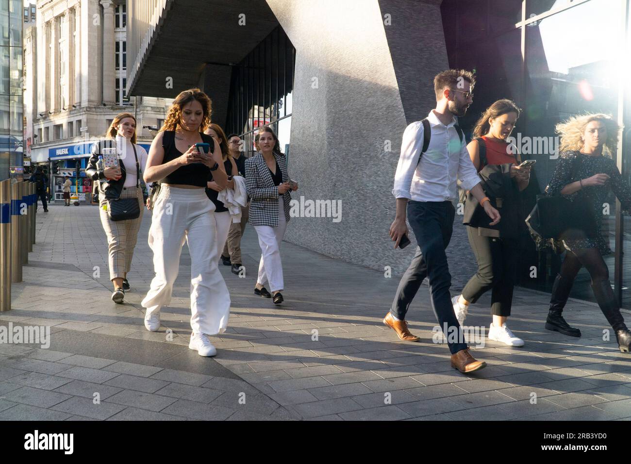 Wetter in Großbritannien, 6. Juli 2023, London: Nach ein paar kälteren Tagen kehrt das warme Wetter nach London zurück und bringt Menschenmassen nach Soho. Am Mittelpunkt kommt Licht aus allen Richtungen, da es von Plattenglasfenstern reflektiert wird, die Schatten in verschiedene Richtungen werfen. Kredit: Anna Watson/Alamy Live News Stockfoto