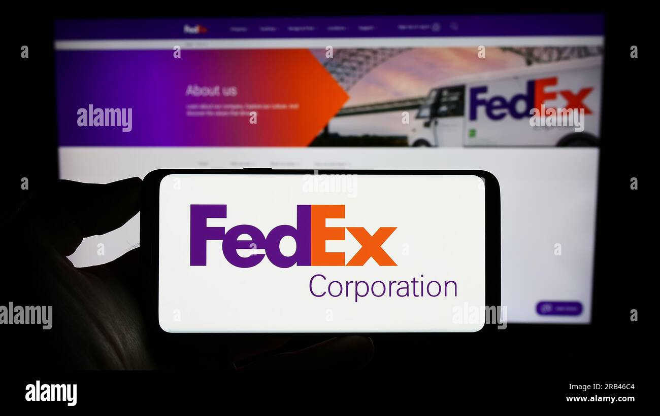 Person, die ein Smartphone mit dem Logo des US-Logistikunternehmens FedEx Corporation auf dem Bildschirm vor der Website hält. Konzentrieren Sie sich auf das Display des Telefons. Stockfoto