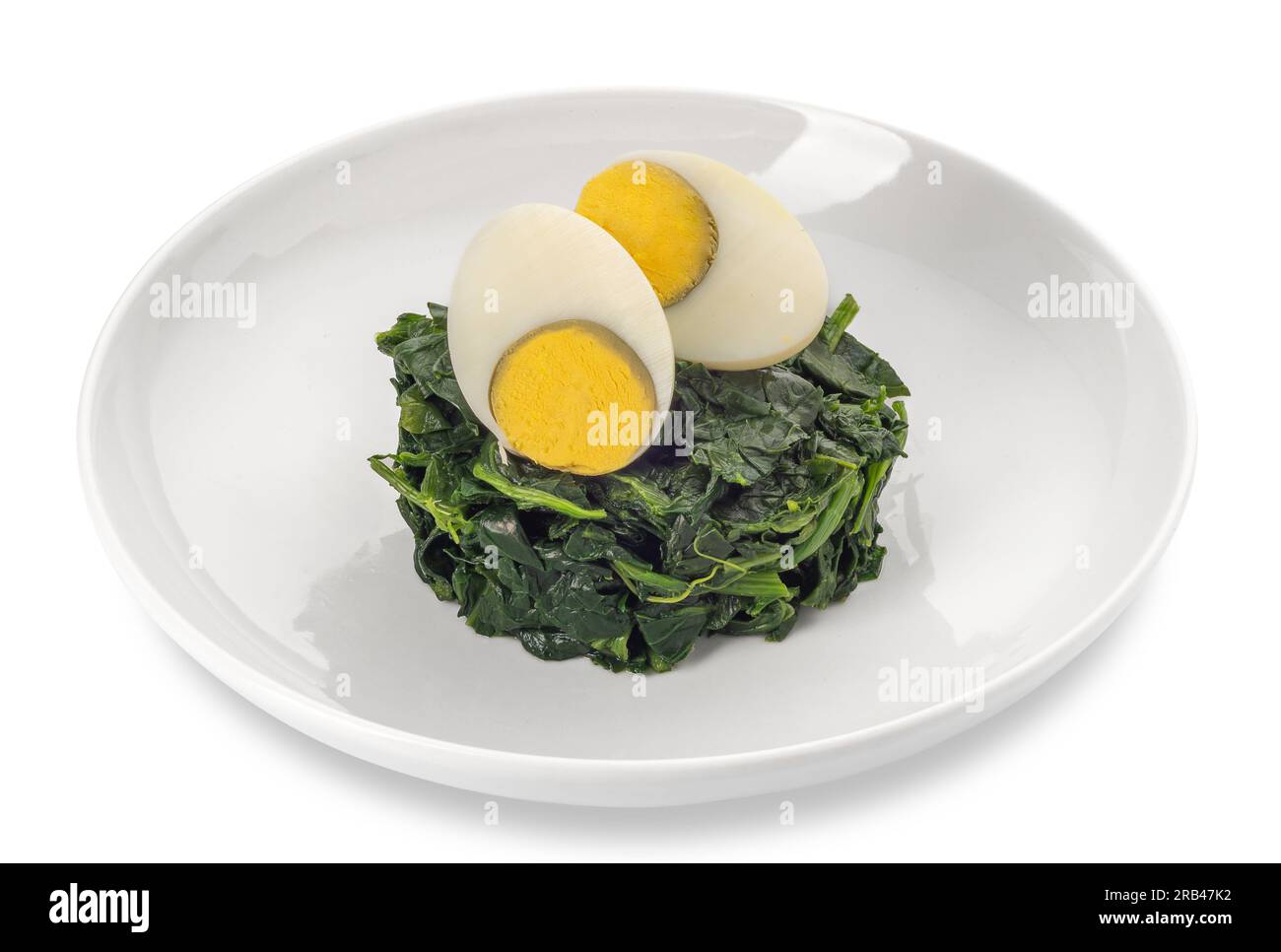 Spinat mit geschnittenem hart gekochtem Ei in weißer Schüssel isoliert auf weißem Boden gekocht, mit Schneideweg im Lieferumfang enthalten Stockfoto