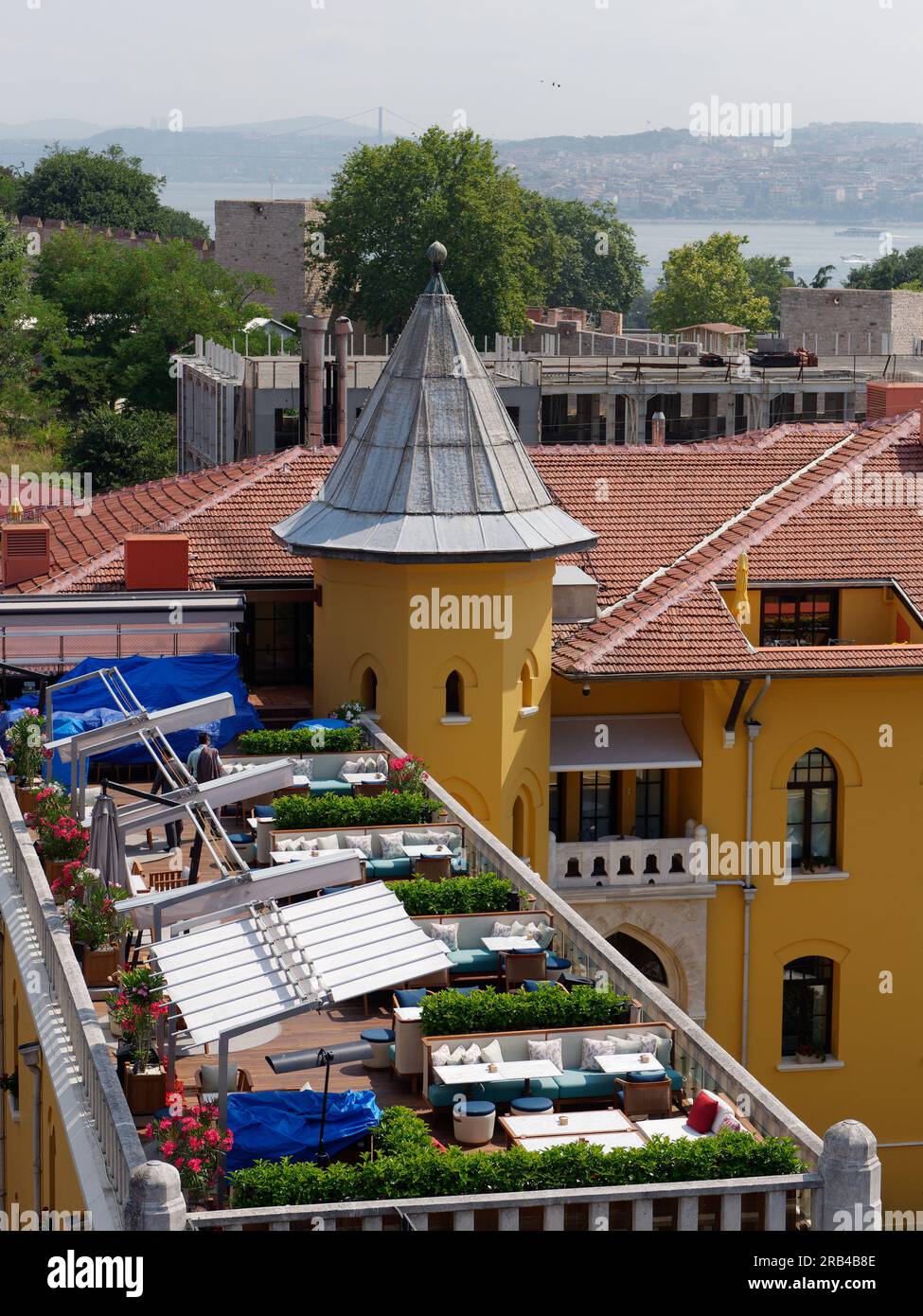 Gelbes Gebäude mit Turm und Terrasse in Form eines Türms und das Bosporus-Meer und die asiatische Seite dahinter in Sultanahmet, Istanbul. Türkei Stockfoto