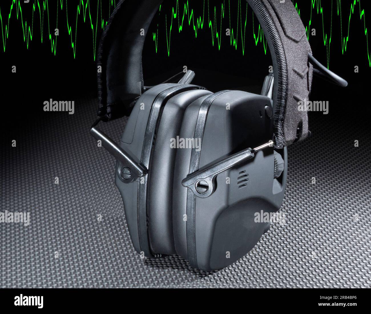 Gehörschutz-Headset für Aufnahmen und Bauarbeiten mit Elektronik und grüner Sinuswelle dahinter Stockfoto