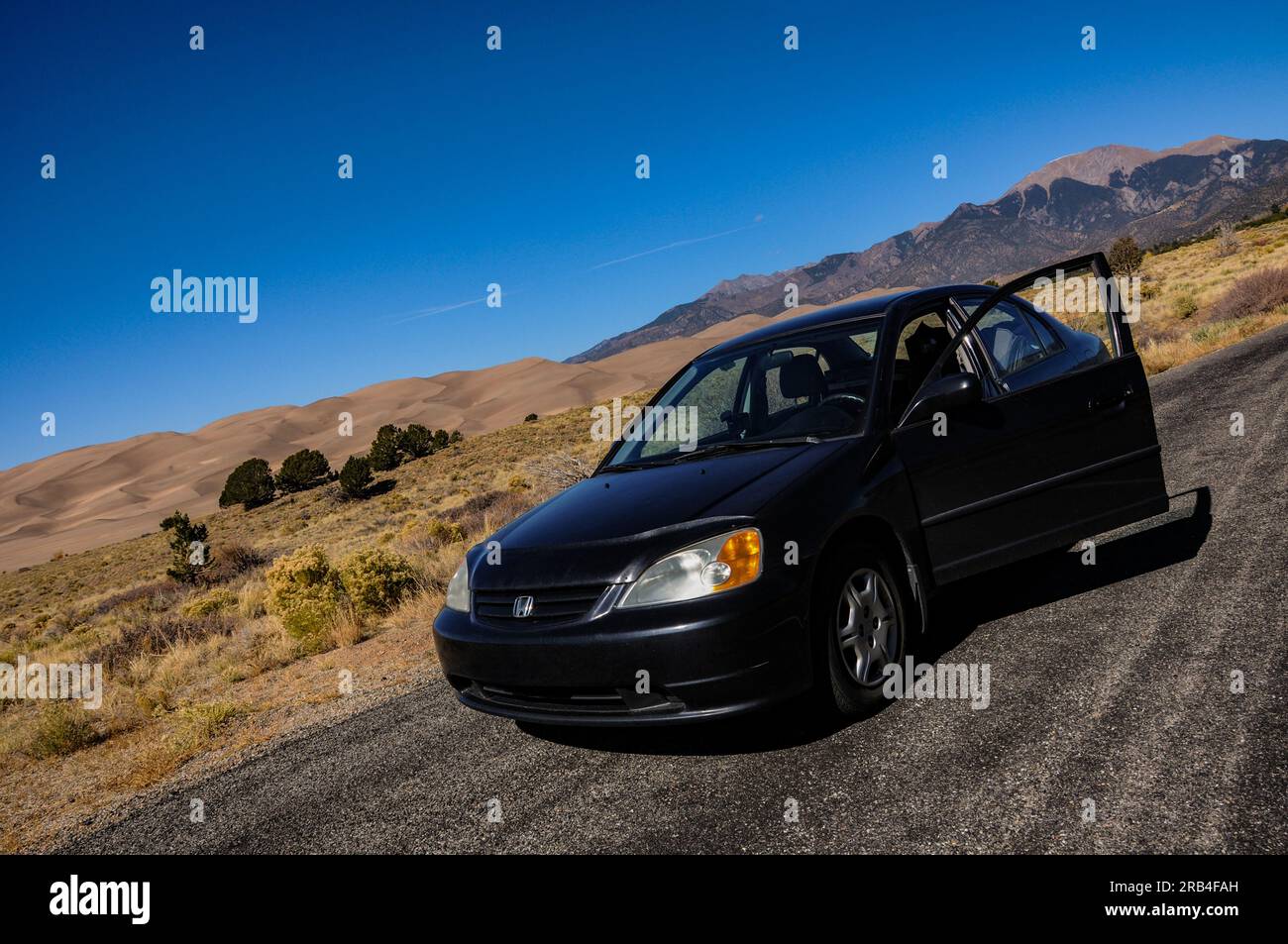 Roadtrip und Auto-Camping in einem schwarzen Honda Civic aus dem Jahr 2002 im Great Sand Dunes National Park in Colorado, USA Stockfoto