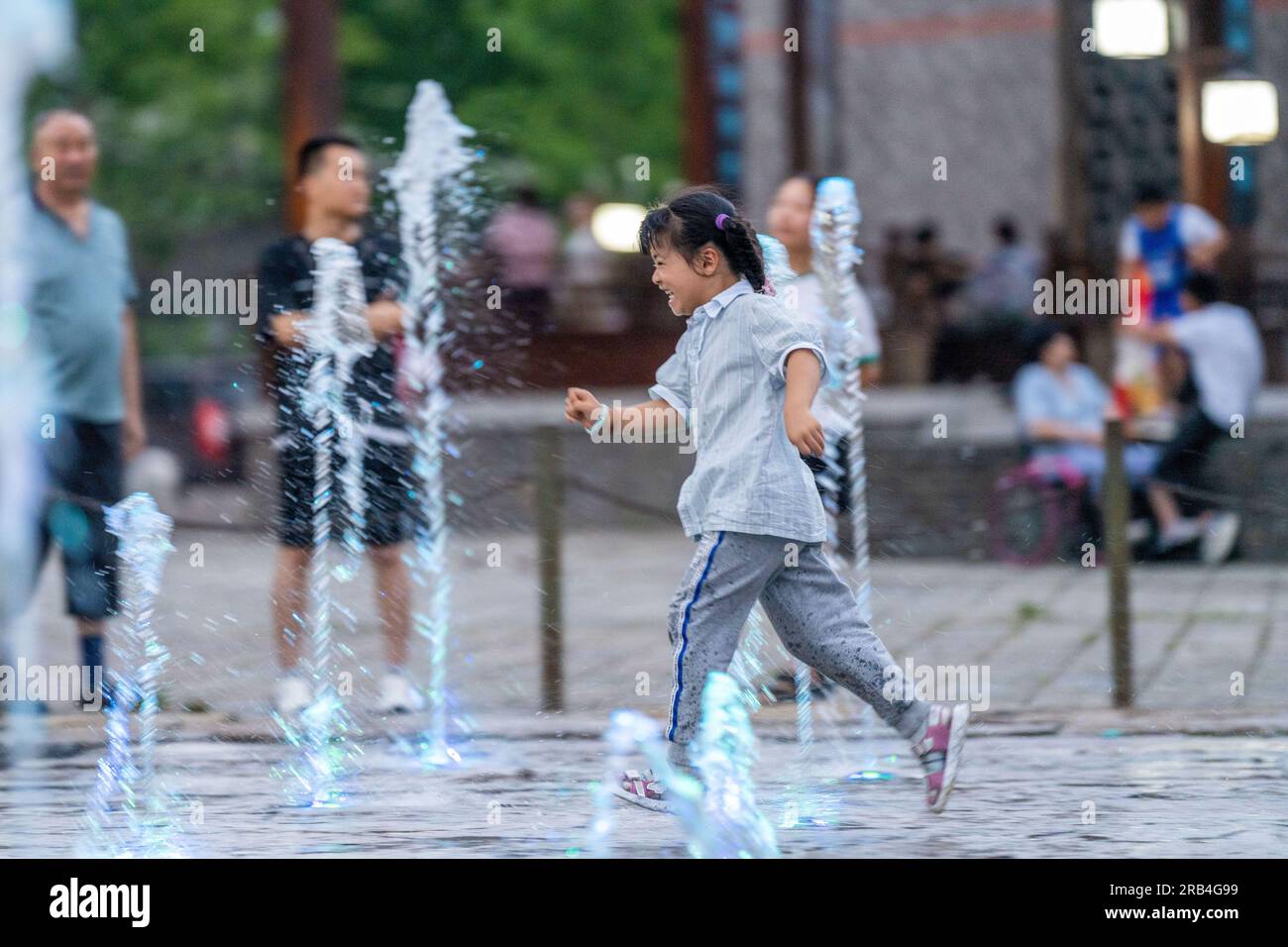 HEFEI, CHINA - 7. JULI 2023 - Kinder spielen mit Wasser, um sich an einem Brunnen auf einem Platz in Hefei, Provinz Anhui, China, abzukühlen, 7. Juli 2023. Stockfoto