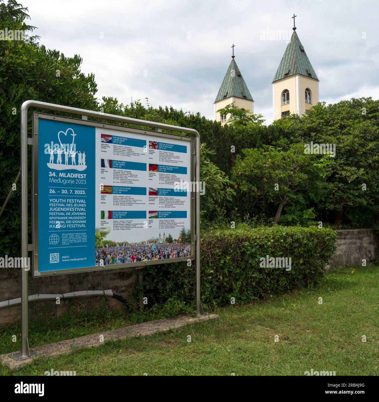 Die zwei Steeples von St. James' Pfarrkirche und das Poster für das Mladifest 2023 Stockfoto