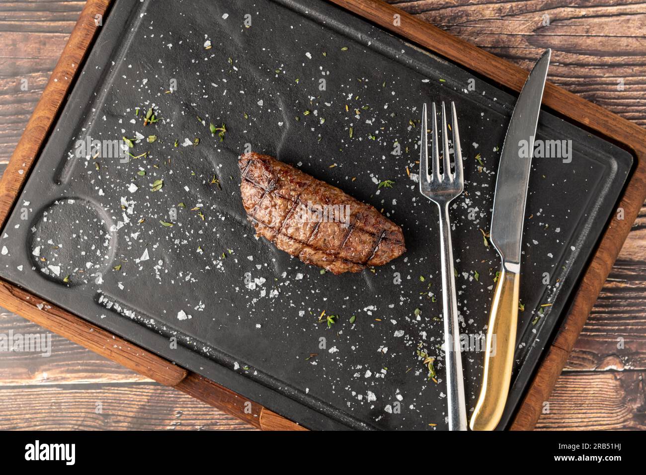 Fleischklößchen mit gegrilltem Cheddar auf einem Steinschneidebrett im Steakhouse-Restaurant Stockfoto