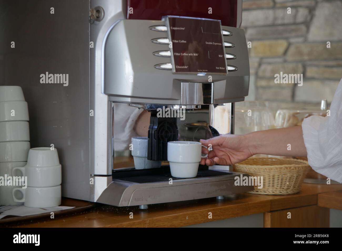 Frau, die Kaffee mit der Kaffeemaschine in der Selbstbedienungs-Cafeteria macht Stockfoto
