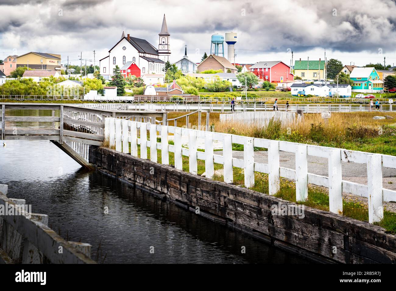 Holzsteg entlang des Old Bay Pond mit historischen Kirchendenkmälern und Wassertürmen mit Blick auf die Stadt Bonavista Neufundland Canada. Stockfoto