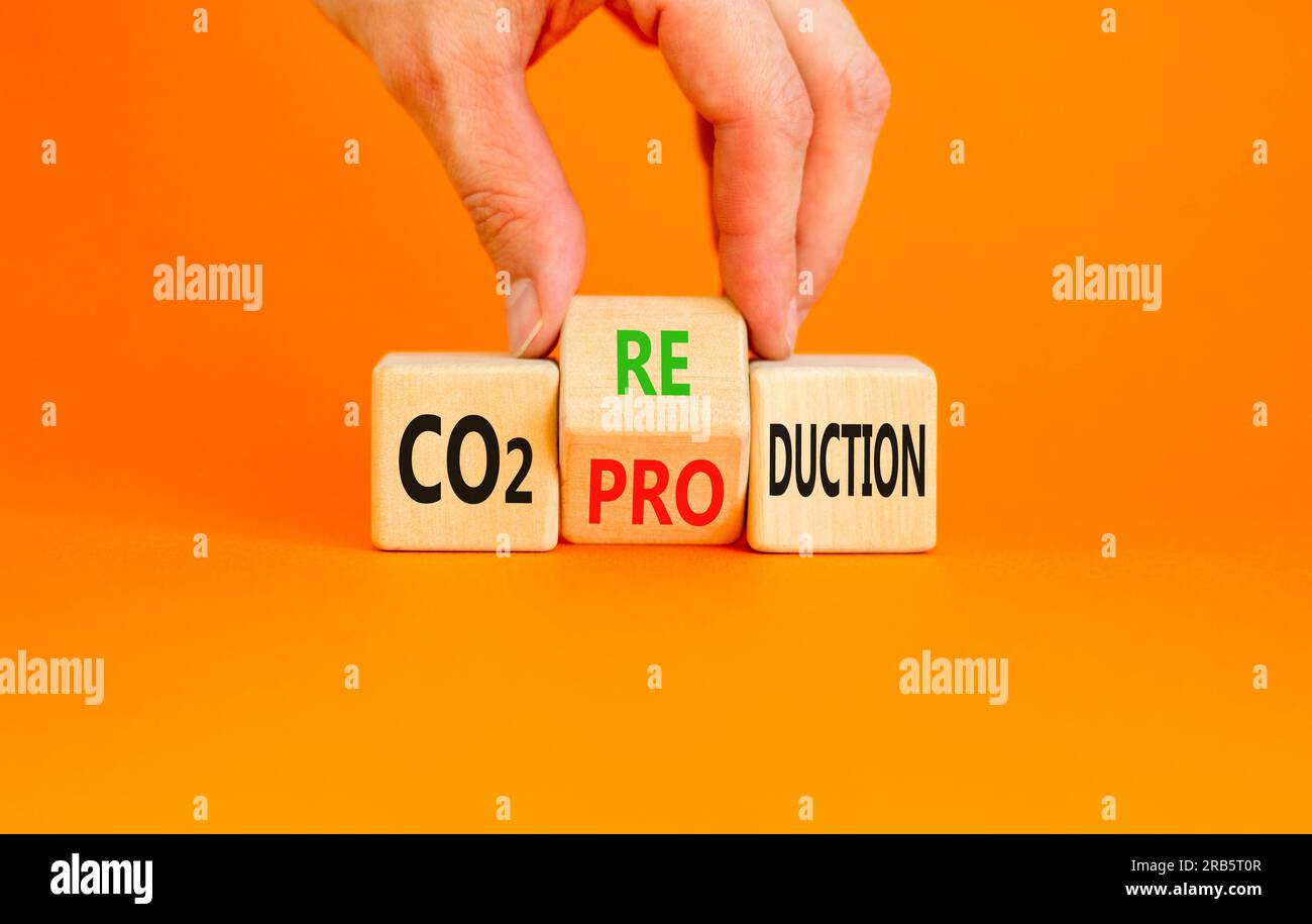 CO2 Symbol für Produktion oder Reduzierung. Konzeptwort CO2 Produktionsreduktion auf einem Holzblock auf einem wunderschönen orangefarbenen Hintergrund. Geschäftsmannshand. Geschäfte Stockfoto