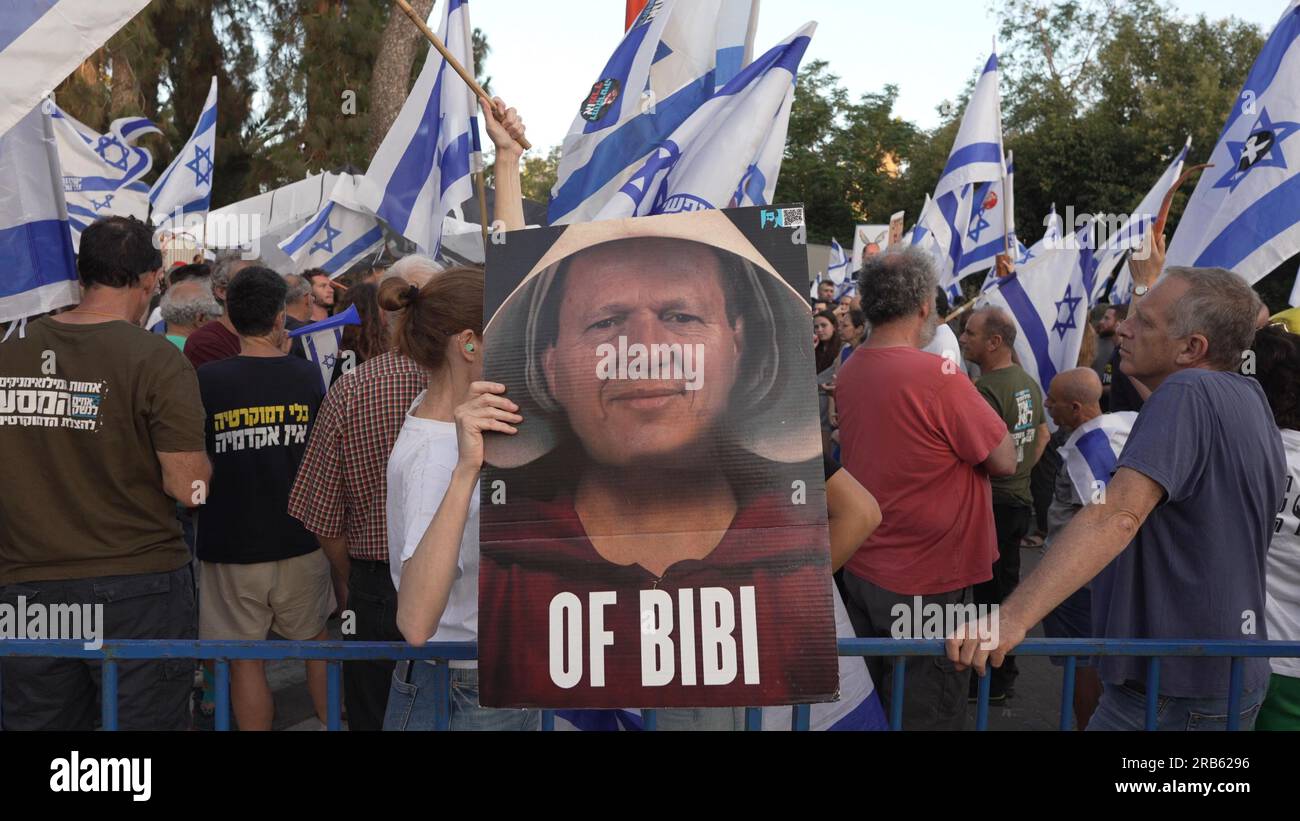 JERUSALEM, ISRAEL - JULI 6: Ein Protestteilnehmer hält ein Schild, auf dem Wirtschaftsminister NIR Barkat in roter Kleidung und weißem Kopfbezug zu sehen ist, Wie die Magd im Roman Margaret Atwood "das Magazin der Magd", während eines Protests von regierungsfeindlichen Demonstranten vor dem Privathaus von Barkat im Rahmen des landesweiten Protests außerhalb der Häuser der Minister bei Protesten gegen die Justizreform am 6. Juli 2023 in Jerusalem, Israel. Stockfoto