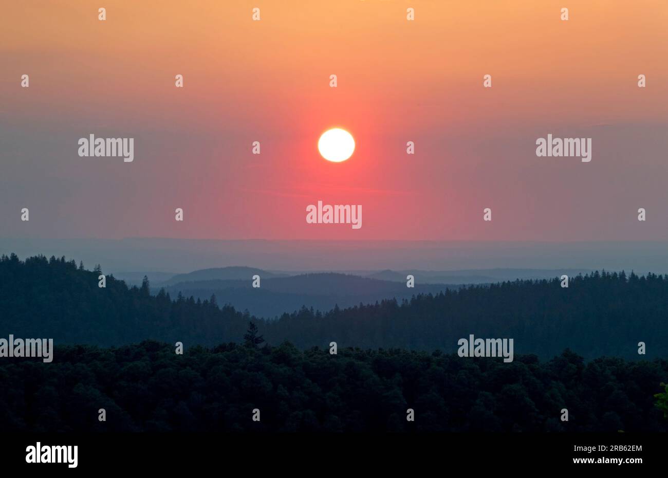 Sonnenuntergang über den Hügeln der Vogesen, orangefarbene Sonne am Abendhimmel, Bergketten in der Ferne verblassen Stockfoto