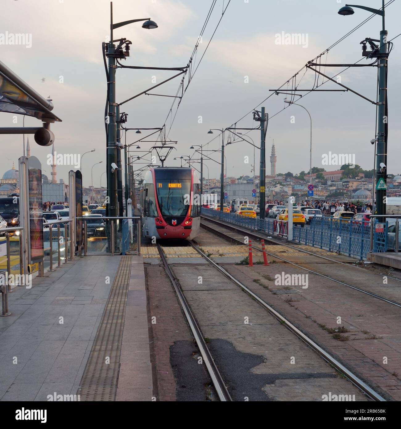 Die Straßenbahn nach Kabatas steht an einem Sommerabend auf der Galata-Brücke, die voller Verkehr ist, einschließlich gelber Taxis. Istanbul, Tur Stockfoto