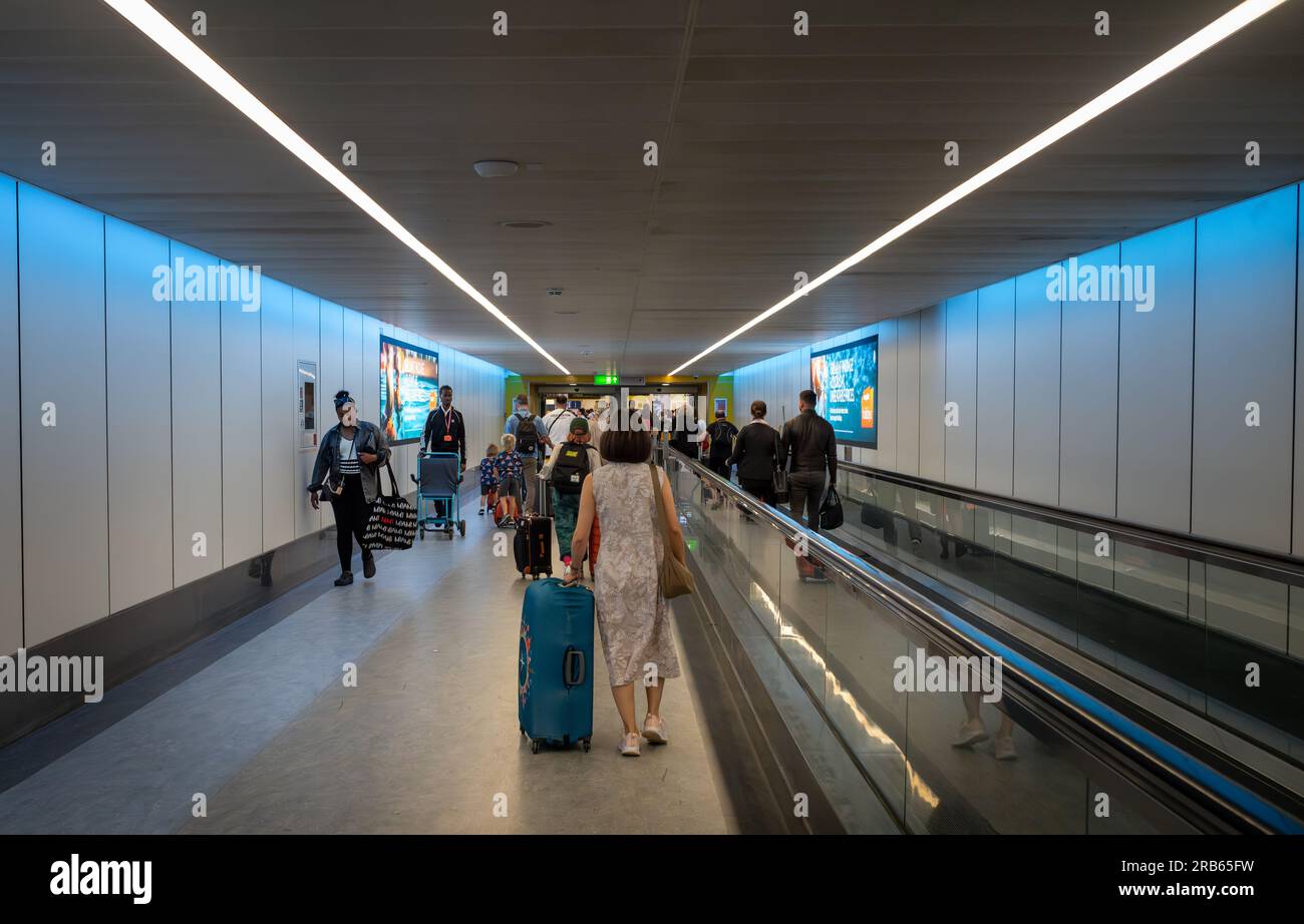 Flughafen Gatwick, London, Großbritannien, 7. Juli 2023. Eine Frau schiebt einen blauen rollenden Koffer neben einen Reisenden zu Abfahrten am Gatwick Airport South Terminal, Großbritannien. In diesem Sommer könnten Tausende von Flügen in Europa verspätet oder annulliert werden, da Fluglotsen mit Streiks drohen. Kredit: Andy Soloman/Alamy Live News Stockfoto