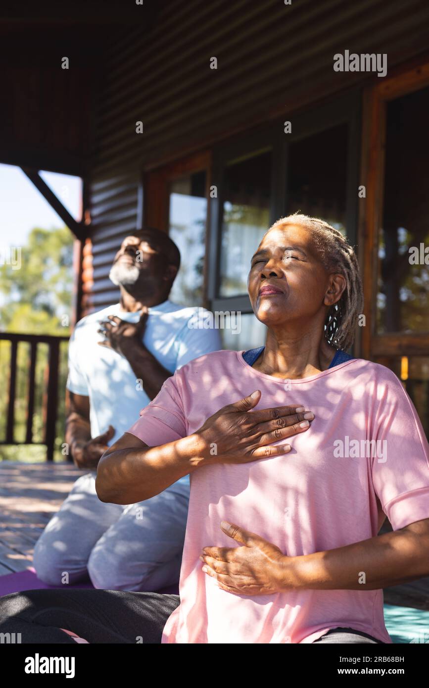 Fokussiertes, hochrangiges afroamerikanisches Paar, das Yoga-Meditation auf der sonnigen Terrasse praktiziert. Senioren-Lifestyle, Entspannung, Wohlbefinden in der Natur, Fitness, Bewegung Stockfoto