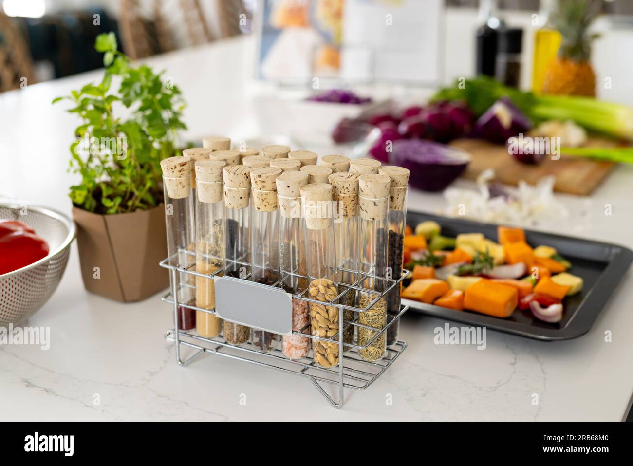 Gewürze in Gewürzregal und gehacktes Gemüse in Backblech auf Arbeitsplatte in sonniger Küche. Kochen, Essen, Zutaten, gesundes Leben und häusliches Leben. Stockfoto