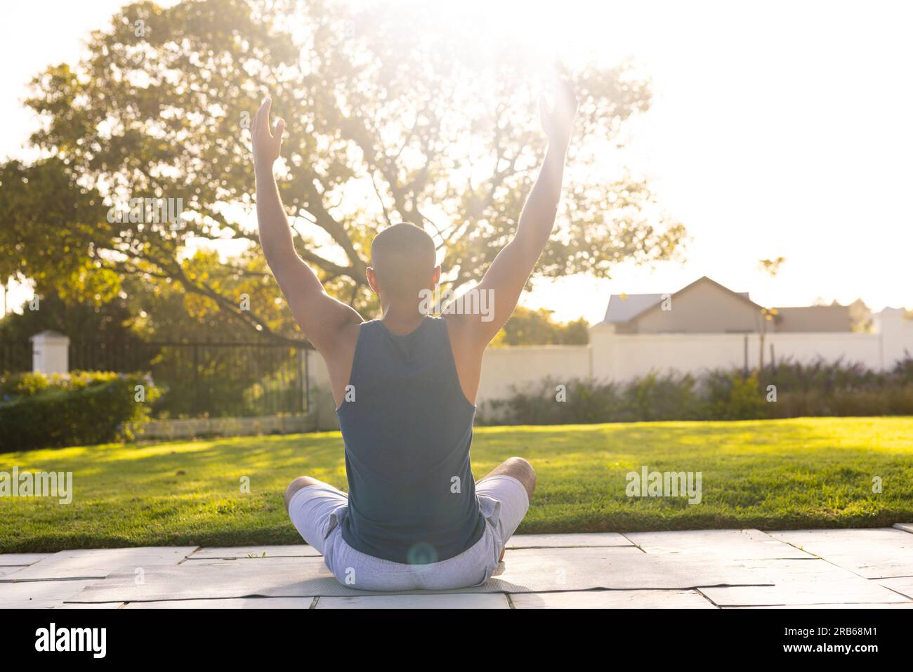 Rückansicht eines birassischen Mannes, der Yoga im sonnigen Garten praktiziert. Sommer, Wohlbefinden, Fitness und gesunder Lebensstil, unverändert. Stockfoto