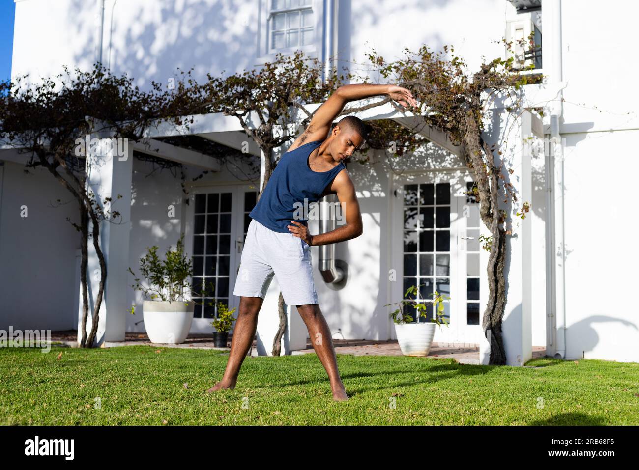 Ein birassischer Mann, der Yoga im sonnigen Garten praktiziert. Sommer, Wohlbefinden, Fitness und gesunder Lebensstil, unverändert. Stockfoto