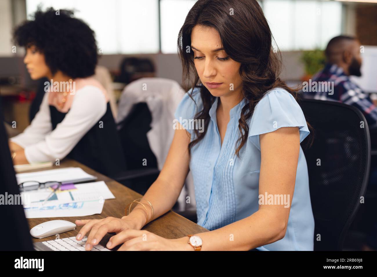 Verschiedene Geschäftsleute, die an Schreibtischen sitzen und Computer im Büro verwenden. Ungezwungene Geschäfte, Kommunikation und Arbeit, unverändert. Stockfoto