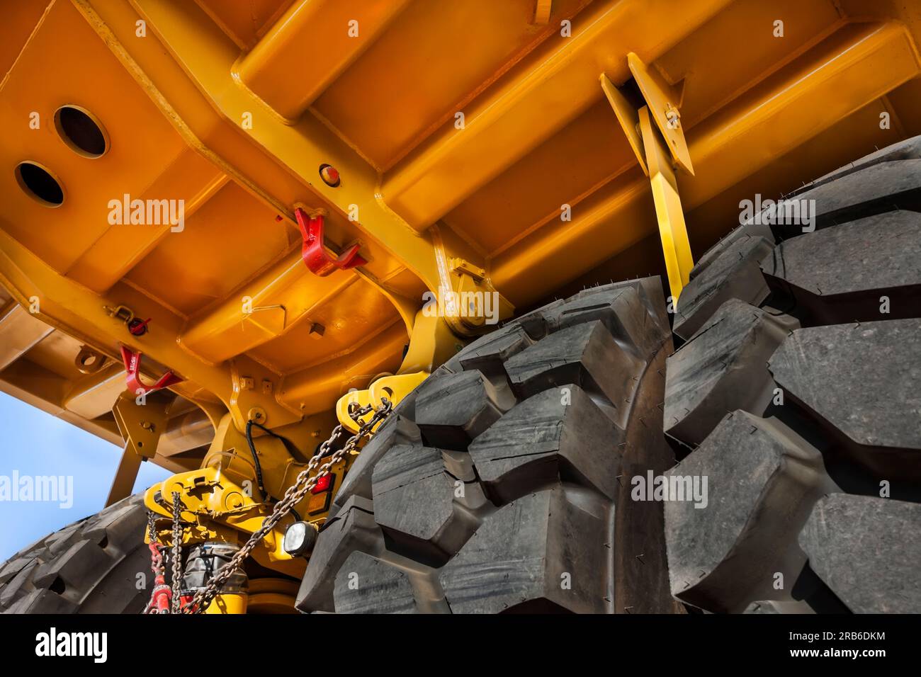 Überarbeitung der Aufhängung, Doppelachse unter einem riesigen, brandneuen gelben Bergbaufahrzeug, oben auf einem Anhänger, der in einer Diamantenmine geliefert wurde Stockfoto