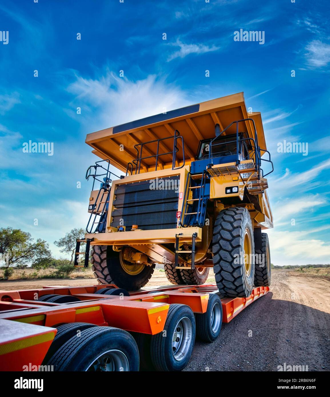 Schwertransporter riesiger gelber Bergbaulaster oben auf einem Anhänger auf einer unbefestigten Straße Stockfoto