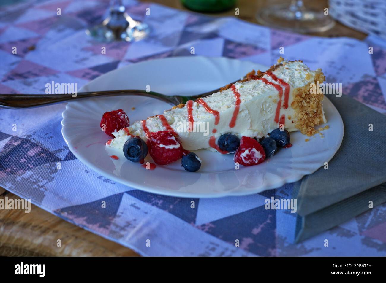 Käsekuchen mit Sahne und Obst auf einem rustikalen Tisch Stockfoto