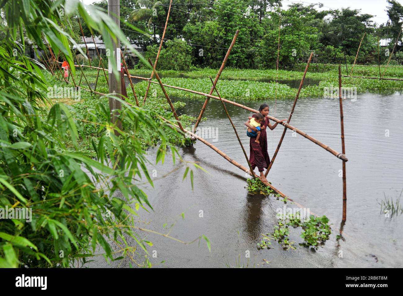 Die Flüsse und Kanäle des Ortes wurden von heftigen Regenfällen überflutet, die unteren Bereiche wurden überflutet. Die Dorfbewohner bewegen sich zu Fuß, einige in Booten, einige überqueren Bambusstangen. Dies ist der Grenzbezirk Sunamganj, der sich im nordöstlichen Teil der Abteilung Sylhet befindet. Sylhet, Bangladesch. Stockfoto