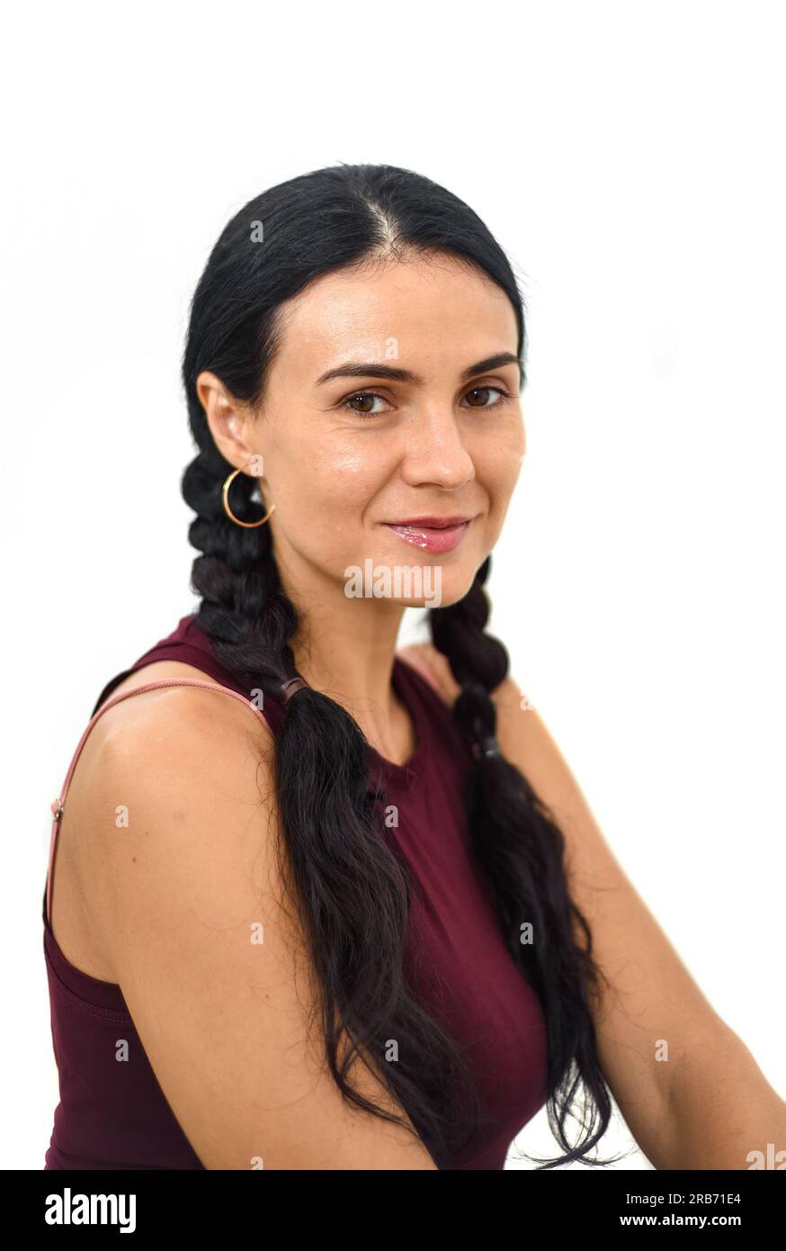 Porträt einer ukrainischen Frau mit Zöpfen, die vor weißem Hintergrund in die Kamera schaut Stockfoto
