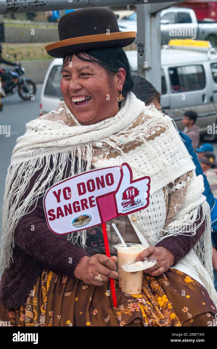 Die fröhliche bolivianische Frau in der Hauptstadt La Paz trägt ein Schild mit der Aufschrift „Ich gebe Blut“ Stockfoto