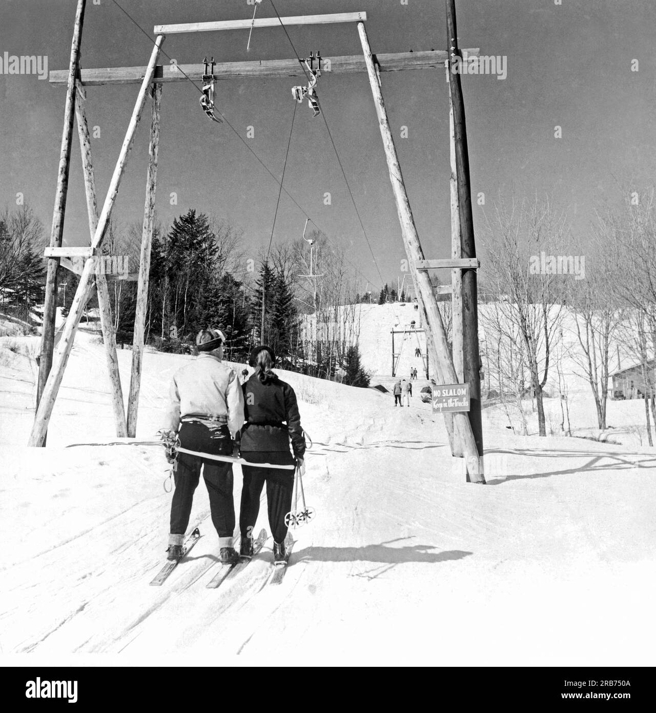 Montreal, Quebec, Kanada: c. 1951. Der T-Bar-Skilift im Skigebiet Laurentian Mountains zieht Skifahrer langsam den Berg hinauf. Stockfoto