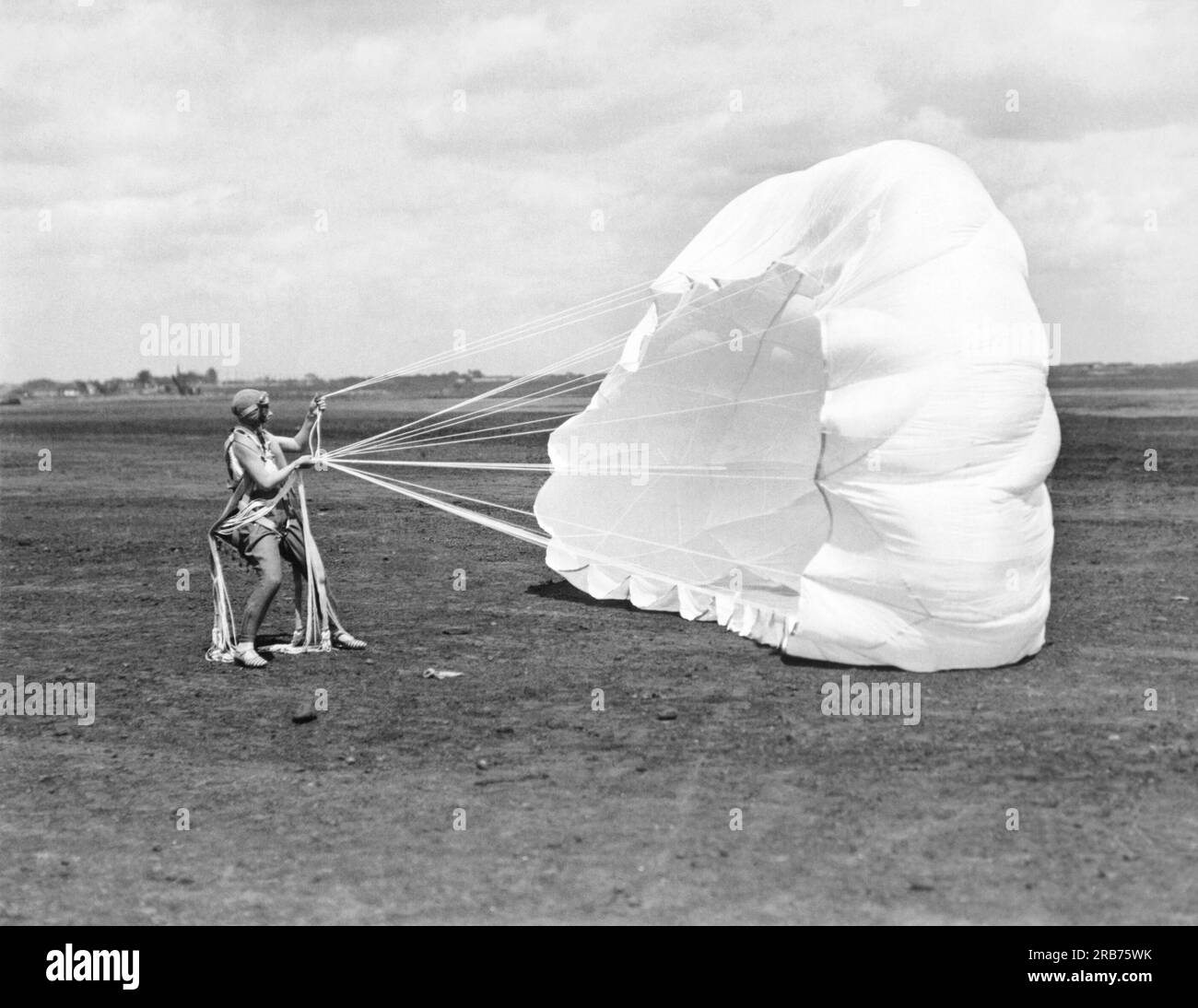 Roosevelt Field, New York: c. 1929 notierte Flugrekordhalter und Aviatrix Elinor Smith schnappt nach der Landung beim ersten Sprung in ihrem Fallschirm nach. Ihr Fallschirm besteht aus amerikanischer Fallschirmseide, die von mehreren amerikanischen Seidenherstellern in Zusammenarbeit mit dem United States Bureau of Standards, dem Handelsministerium, dem Navy Department und der Silk Association of America entwickelt wurde. Dieses Fallschirmgewebe wurde jetzt vom Navy Department für den offiziellen Gebrauch angenommen. Stockfoto