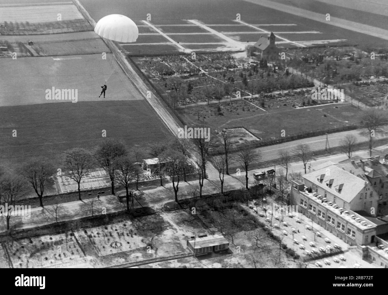 Deutschland: 24. Mai 1931 Willi Ruge ist bestrebt, die ersten Selbstporträts vom Fallschirm zu machen, wenn er aus einem Flugzeug springt. Hier fotografiert er sich selbst, während er hinabsteigt, ist aber auch besorgt über die Hochspannungsleitungen unten. Stockfoto