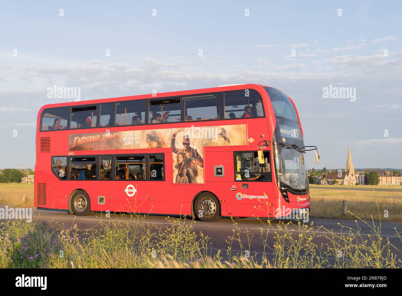 Blick von der Seite auf den roten Doppeldeckerbus mit offenem Oberdeck, der die Menschen während der abendlichen Hauptverkehrszeit in Greenwich London UK nach Hause bringt Stockfoto