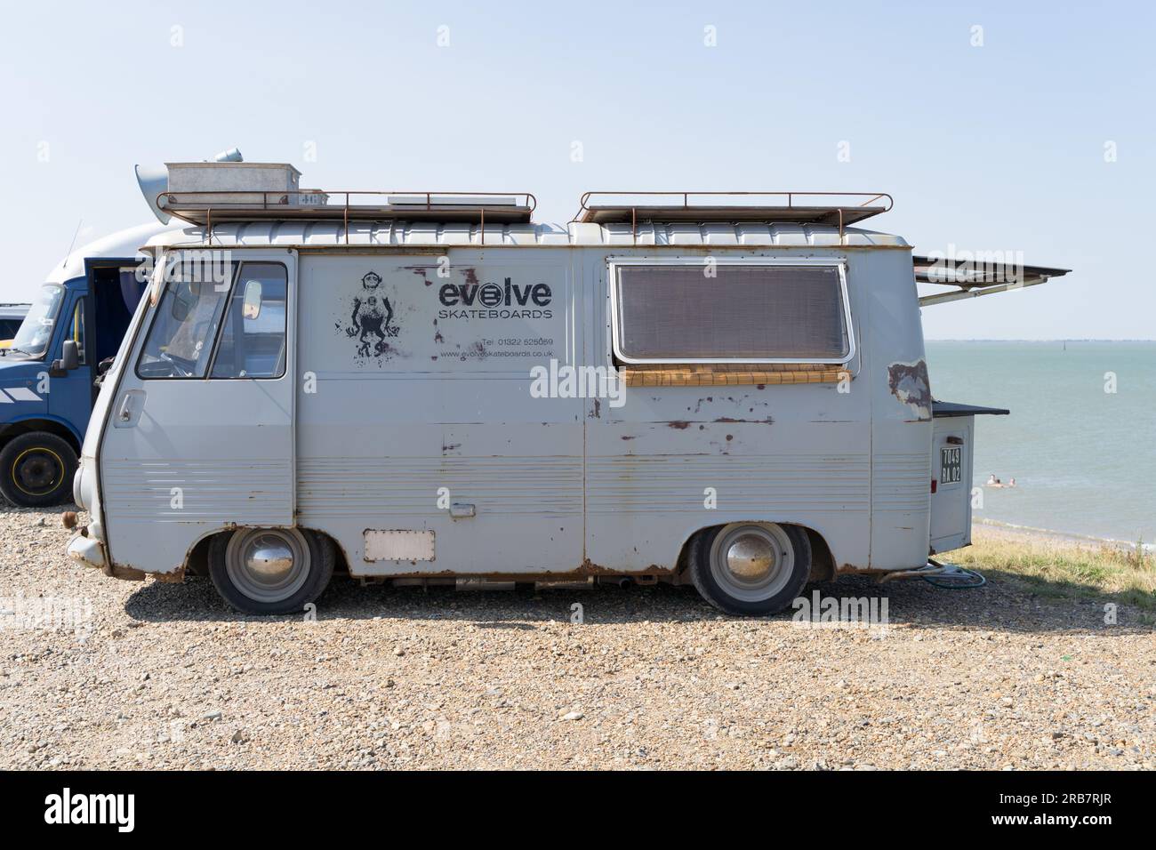 Seitenansicht des Peugeot Wohnwagens des Urlaubers mit Dachgepäckträger, ausgestattet mit einem lauten Lautsprecher, Koffern , Evolve Skateboards , am Meer Kent England UK Stockfoto
