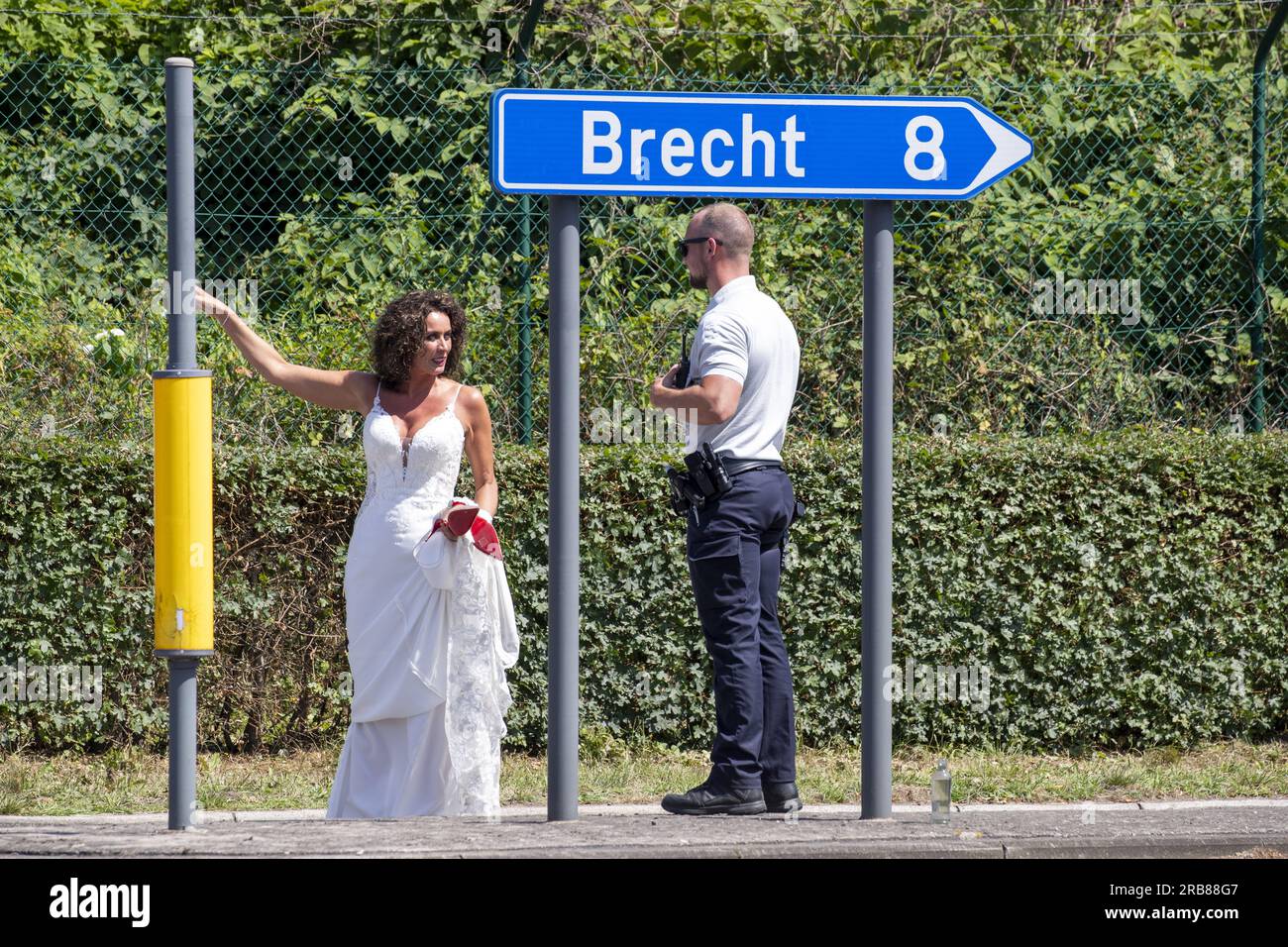 Wustwezel, Belgien. 08. Juli 2023. Eine Frau auf dem Weg zu ihrer Hochzeit kommt an einer illegalen Rave-Party im Militärgebiet Groot Schietveld vorbei, an der Grenze zwischen Brecht und Wustwezel, Provinz Antwerpen, Sonntag, den 09. Juli 2023. Etwa 200 Personen waren auf der Party anwesend. Antwerpener Gouverneur Berx hat den Notfallplan der Provinz aktiviert. Die Polizei hat den Zugriff auf die Seite blockiert. BELGA FOTO NICOLAS MAETERLINCK Kredit: Belga News Agency/Alamy Live News Stockfoto