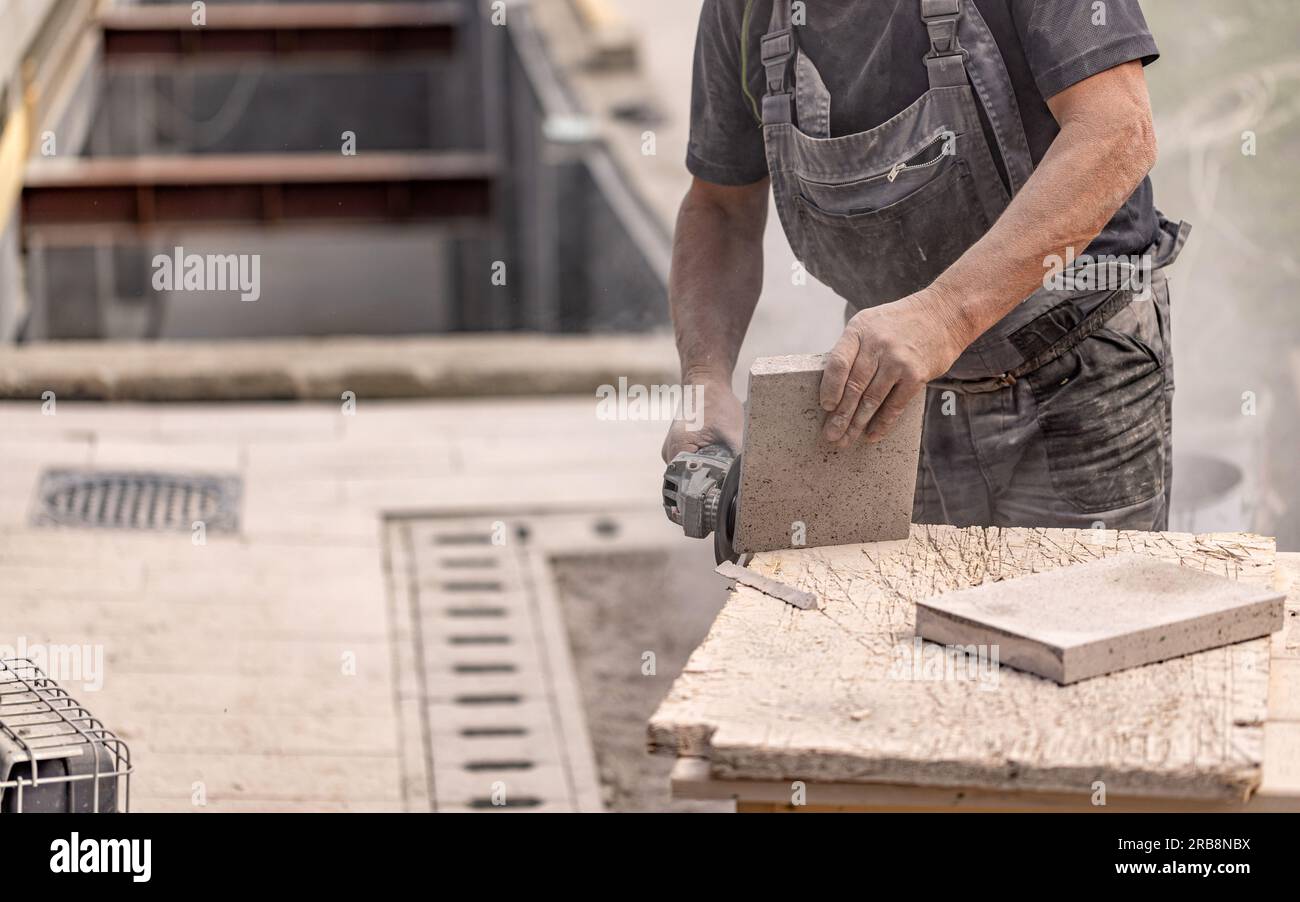 Nahaufnahme der Arbeiterhand mit der Kreissäge beim Schneiden von Steinen für die Pflasterbefestigung Stockfoto