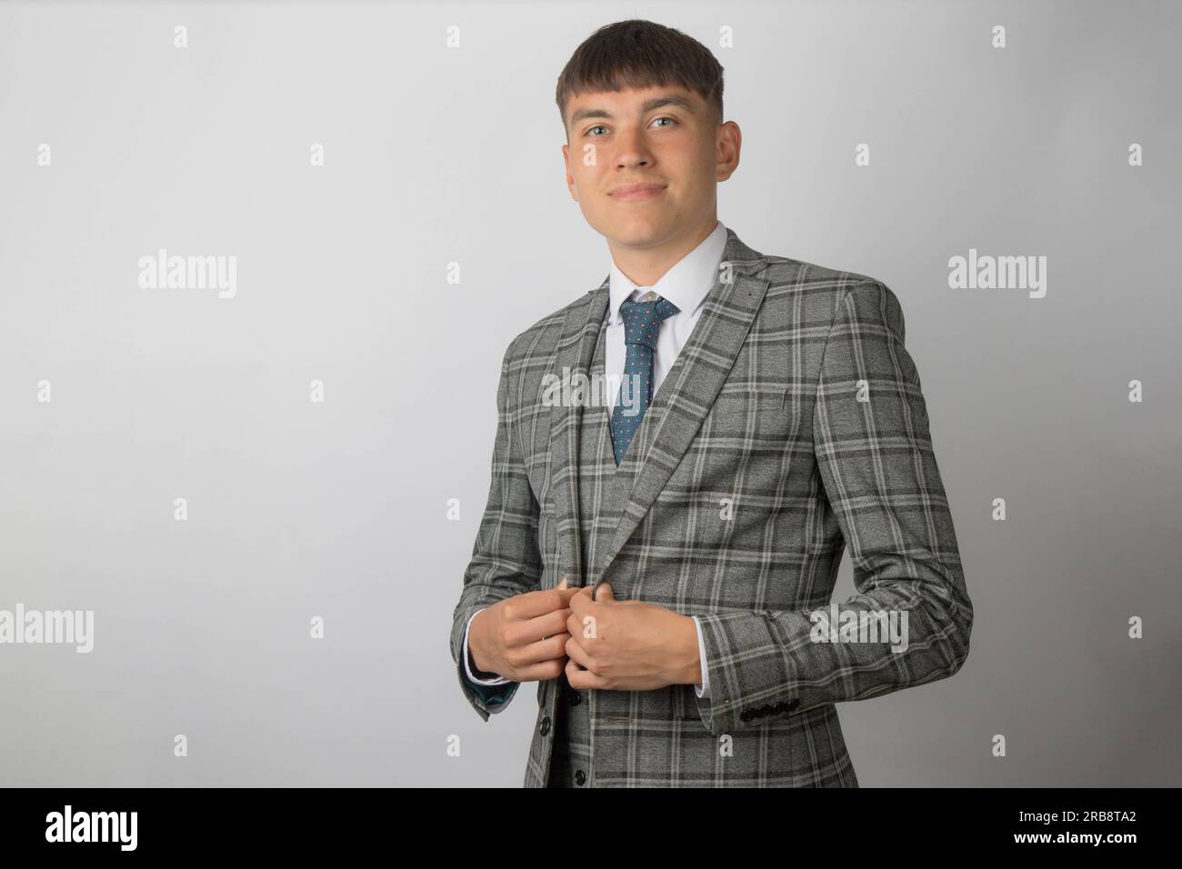 Junger Unternehmer, der Anzug, Krawatte und Weste trägt und seinen Jackenknopf hochdrückt Stockfoto