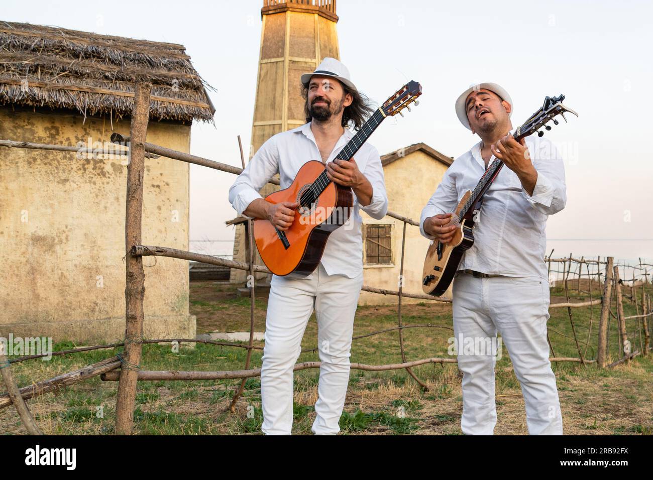 Musiker in weißen Kleidern und weißen Hüten spielen Gitarren. Stockfoto
