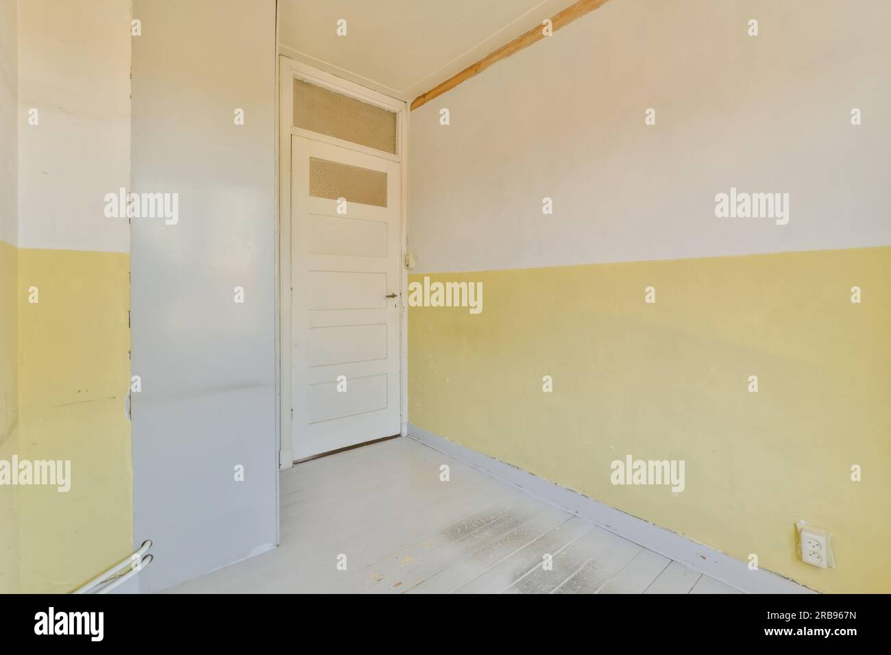 Ein leerer Raum mit gelber Farbe an den Wänden und weißer Verkleidung um die Tür, die entfernt wurde Stockfoto