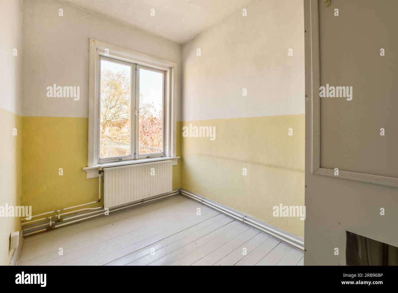 Ein leerer Raum mit gelber Farbe an den Wänden und weißen Bodenbrettern vor dem Fenster Stock photo Stockfoto