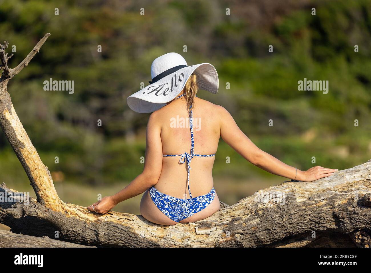 Eine junge Frau mit weißem Hut sitzt auf einem Sandstrand, Rab Island, Kroatien Stockfoto