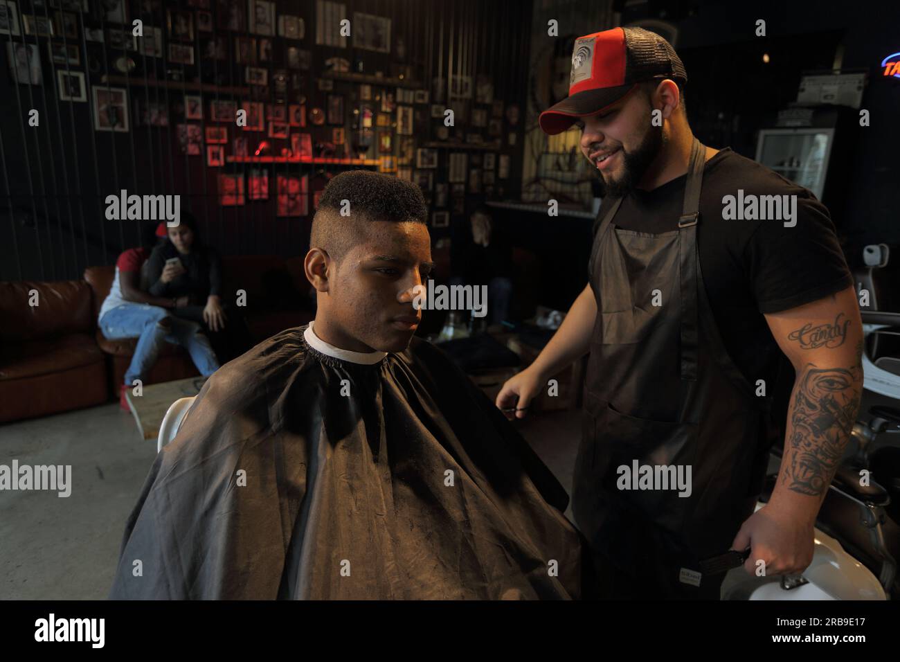 Friseurin, der den Kunden im Salon bedient. Ein junger Mann bekommt einen trendigen Haarschnitt im Friseursalon. Frankfurt am Main, Deutschland Stockfoto