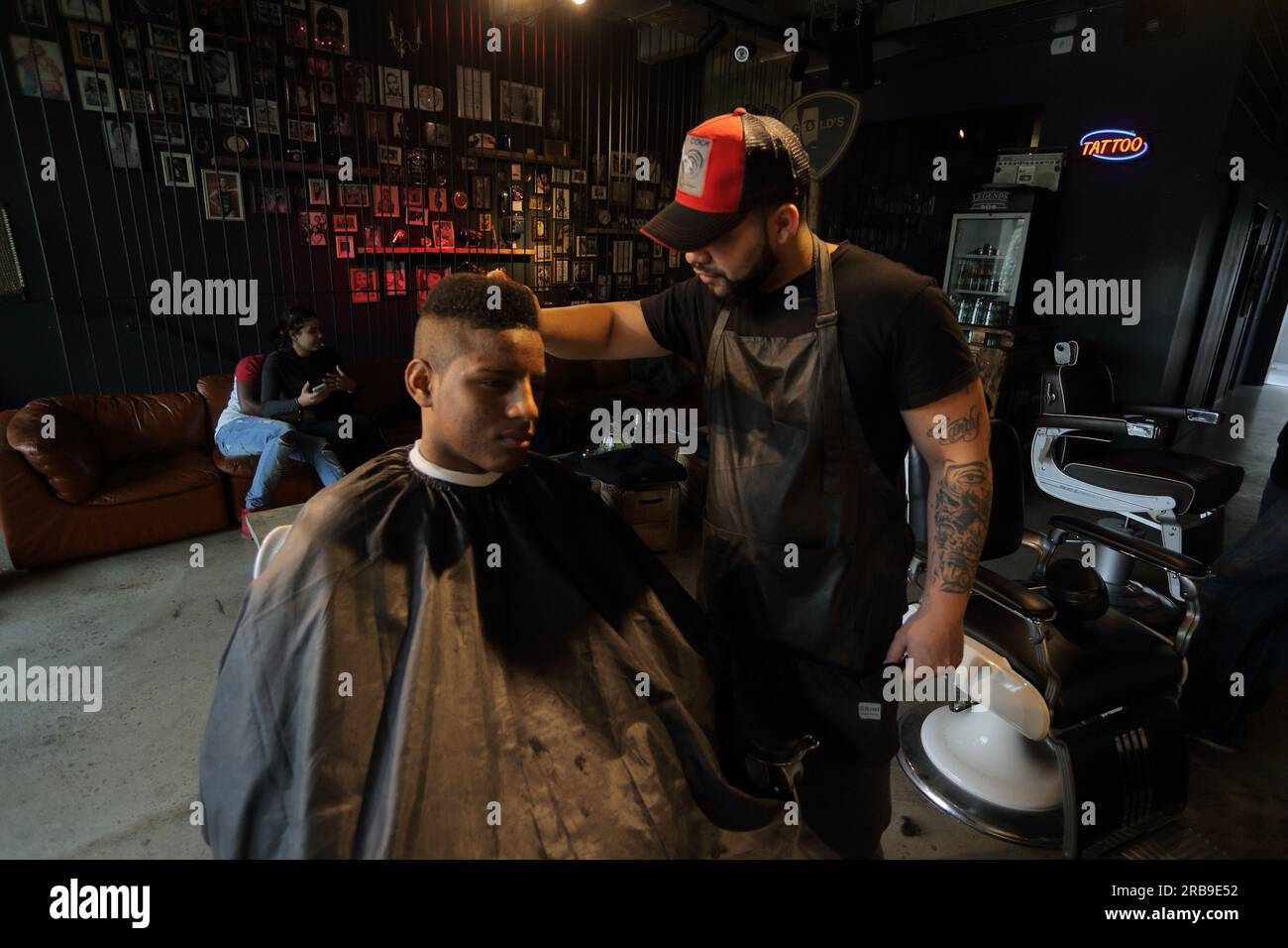 Friseurin, der den Kunden im Salon bedient. Ein junger Mann bekommt einen trendigen Haarschnitt im Friseursalon. Frankfurt am Main, Deutschland Stockfoto