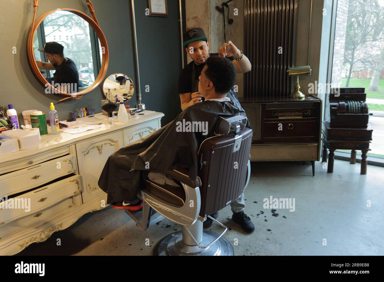 Professioneller Friseur, der männliche Klienten im Friseursalon auf einem Stuhl bedient. Frankfurt am Main, Deutschland Stockfoto