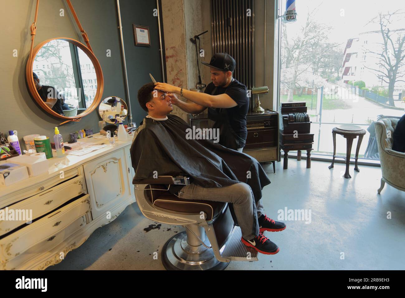 Professioneller Friseur, der männliche Klienten im Friseursalon auf einem Stuhl bedient. Frankfurt am Main, Deutschland Stockfoto
