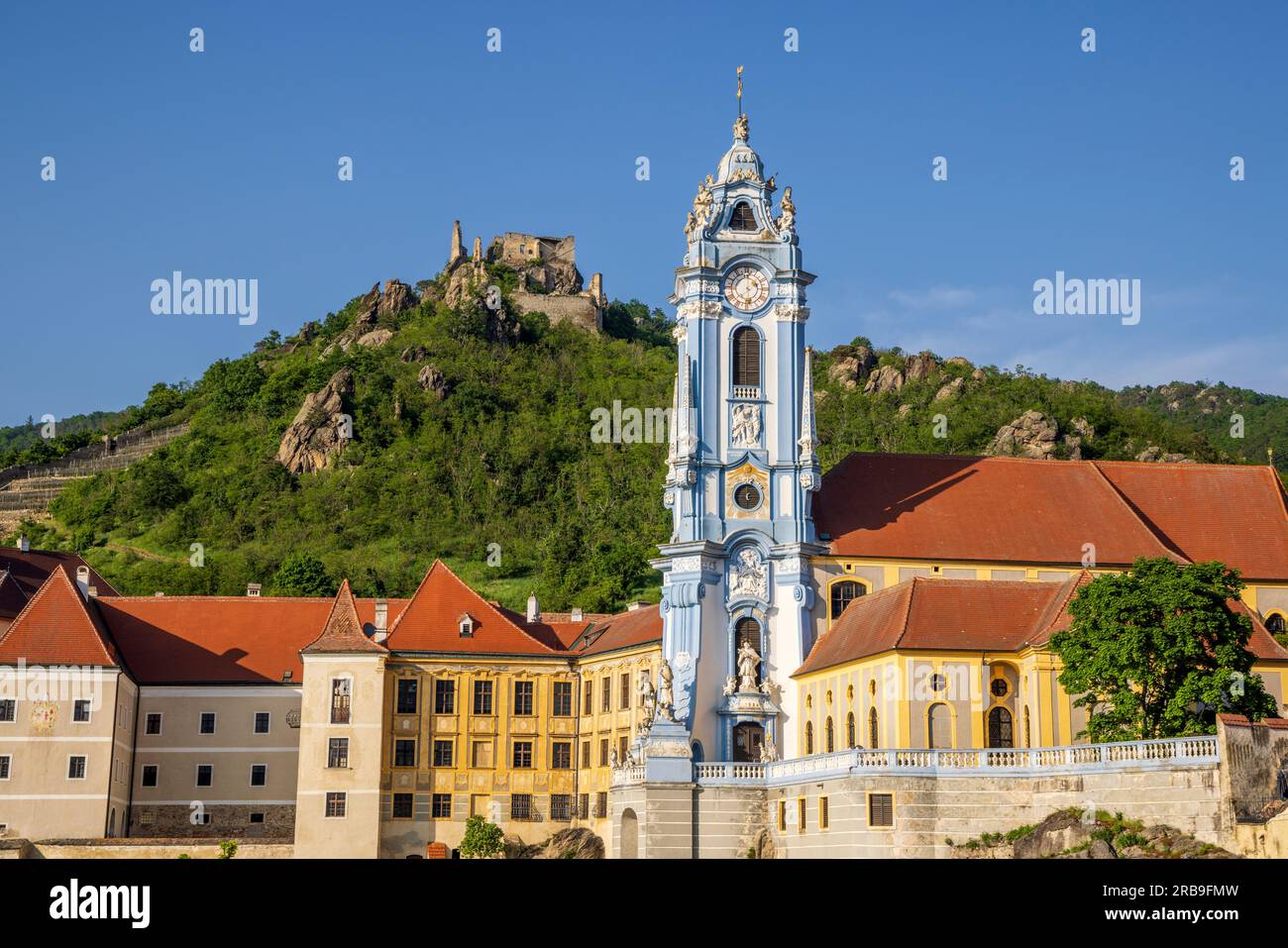 Die Blaue Kirche in Durnstein an der Donau mit Burgruine Burg auf einem Hügel, Niederösterreich Stockfoto