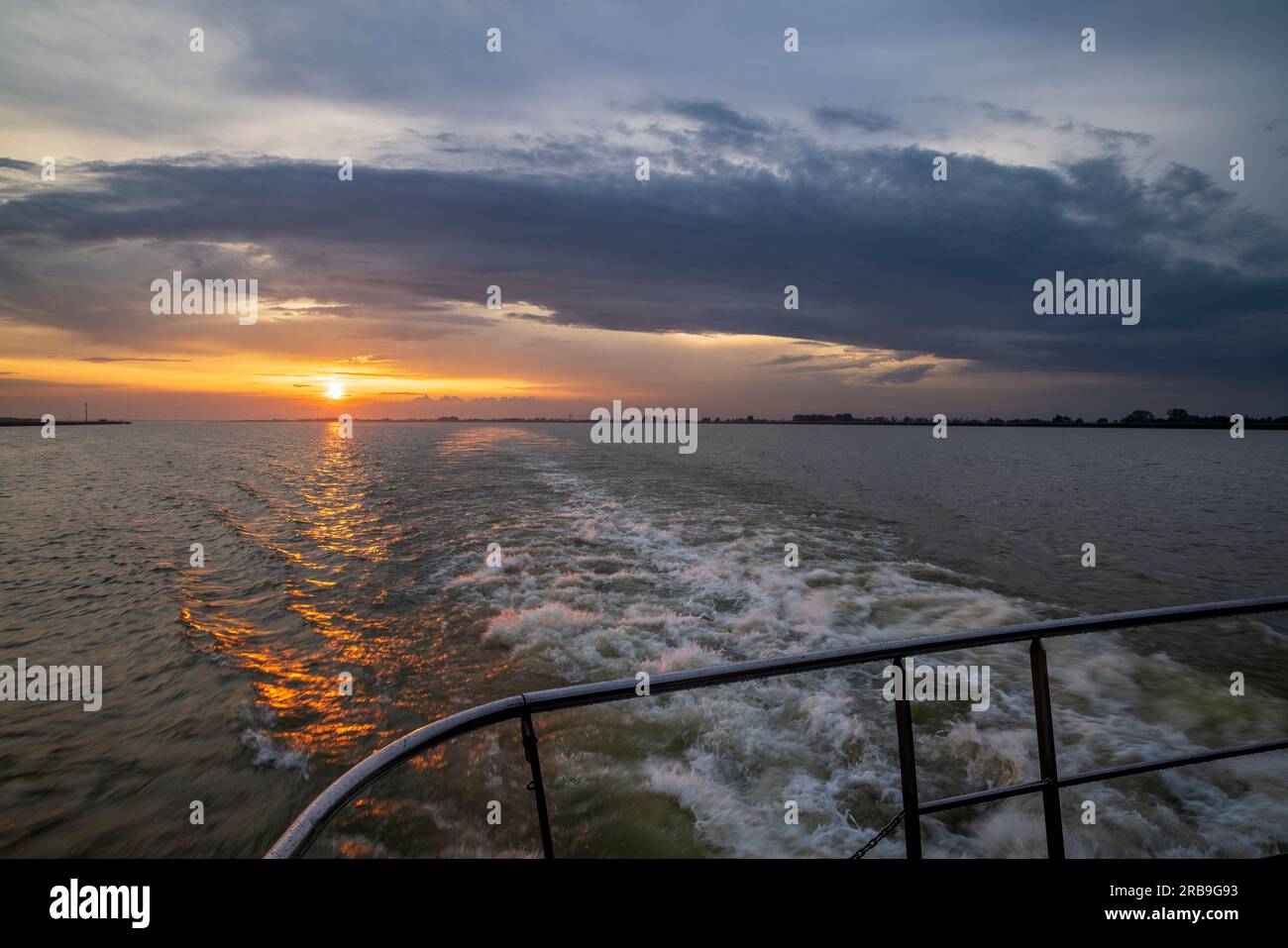 Fahrt Richtung Osten entlang der Donau bei Sonnenuntergang vom Heck einer Bootstour auf dem ungarischen Fluss Stockfoto