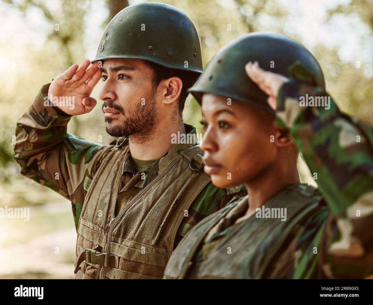 Soldat, Militär, Mann und Frau salutieren in der Natur für Dienst, Schutz und Schlacht im Freien. Kriegstraining, Nationalarmee und Leute in Position Stockfoto
